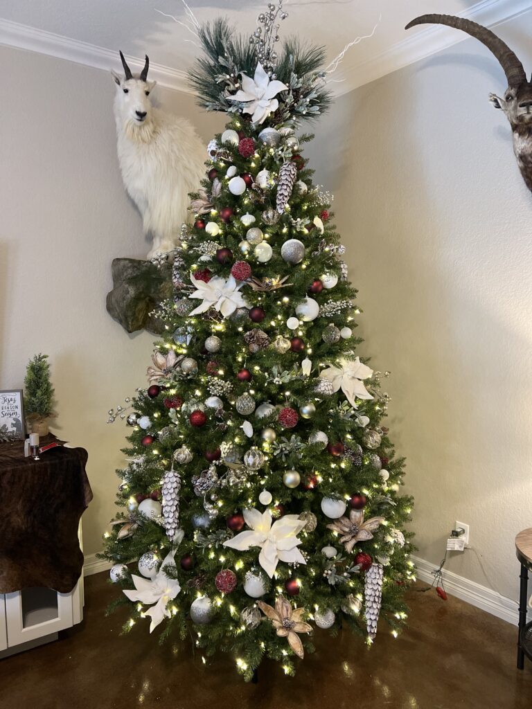 A richly decorated Christmas tree with white flowers