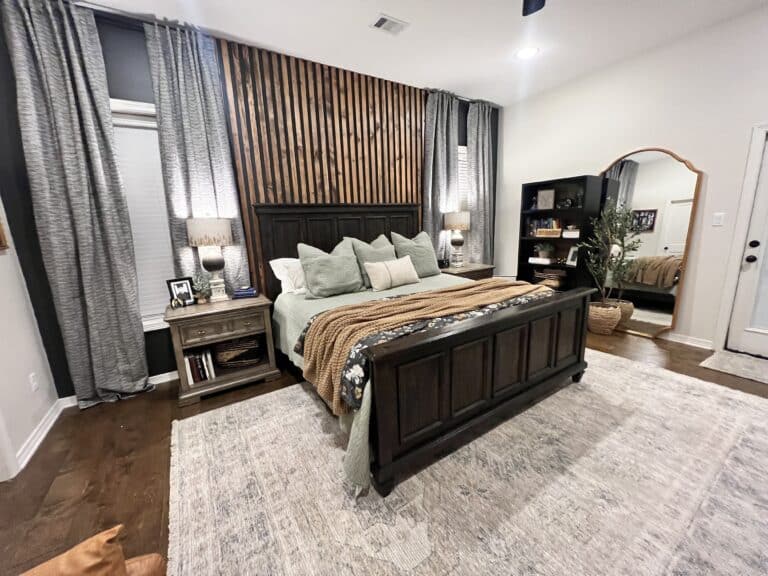 A modern bedroom with a dark wood king-sized bed, grey bedding, and a unique wooden slat feature wall.