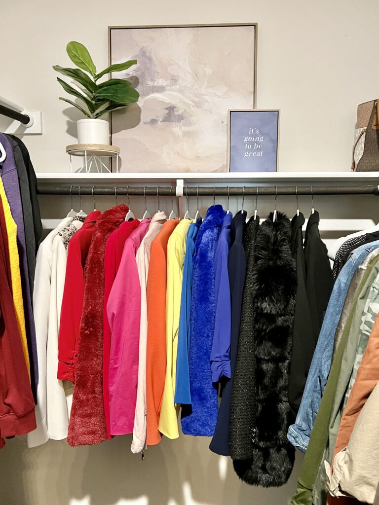 A closet featuring a row of colorful clothes on hangers